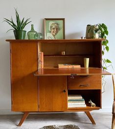 a wooden cabinet sitting on top of a floor next to a table with a chair