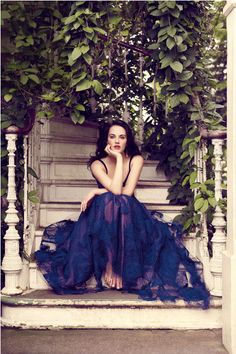 a woman in a blue dress sitting on a porch