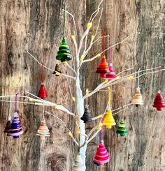 a white tree with many colorful ornaments hanging from it's branches on a wooden wall