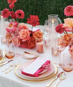 the table is set with pink flowers and gold place settings for an elegant wedding reception