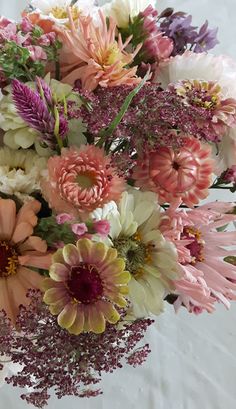 a vase filled with lots of different colored flowers on top of a white table cloth