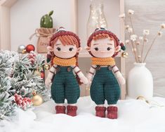 two crocheted dolls standing next to each other in front of a christmas tree