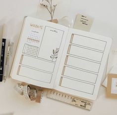 an open planner book sitting on top of a table next to some pens and pencils