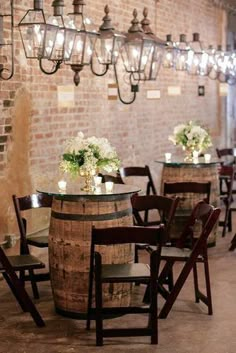 tables and chairs are set up with wine barrels as centerpieces