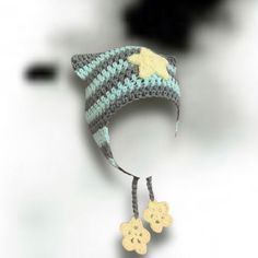 a crocheted hat with a star on it is hanging from a string and has two small buttons attached to the side