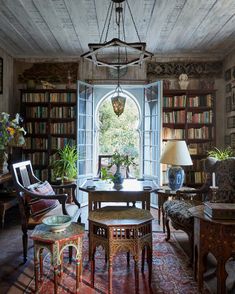 a living room filled with lots of furniture and bookshelves next to a window