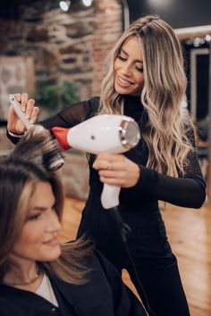 a woman blow drying another woman's hair