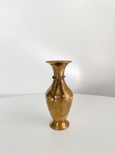 a gold vase sitting on top of a white table