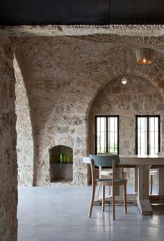 a room with stone walls and tables in the center, surrounded by two archways