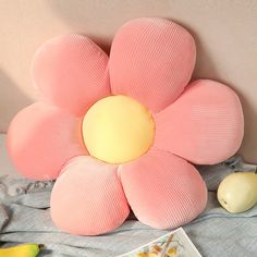 a pink flower pillow sitting on top of a bed next to an egg and banana