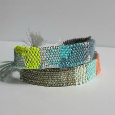 two bracelets with different colors and designs on white surface, one has a feather in the middle