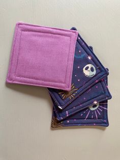 three purple coasters with skulls and stars on them, one has a pink cloth backing