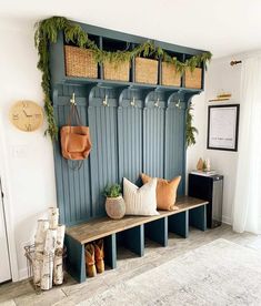 a bench with baskets and plants on it in front of a wall mounted coat rack