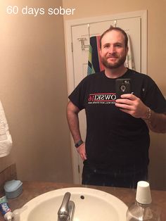 a man taking a selfie in the bathroom mirror with his cell phone and toothbrushes