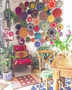 a room filled with lots of different colored plates hanging on the wall next to a wooden table