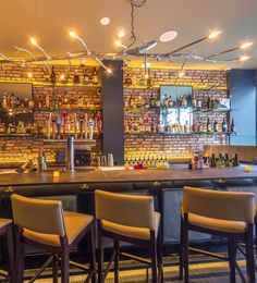 a bar with several stools and bottles on the wall