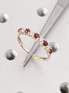 a diamond and ruby ring sits on top of screwdrivers, surrounded by studs