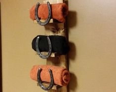 three pairs of black and orange towels hang on a wooden rack with metal rings attached to them