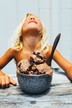 a woman sitting at a table with an ice cream sundae in front of her