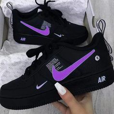 someone is holding up their black and purple nike air force sneakers