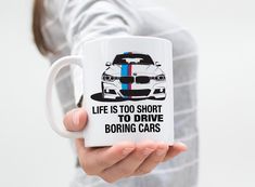 a person holding a coffee mug with a bmw car on it