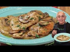 an older man holding a glass of wine next to a plate of chicken and mushrooms