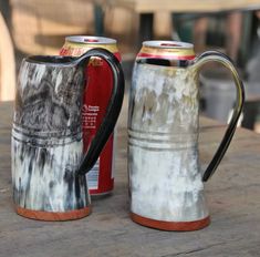 two beer mugs sitting on top of a wooden table