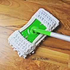 a green and white mop sitting on top of a wooden floor next to a cleaning brush