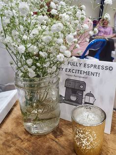 there is a vase with flowers in it next to a glass filled with water and a sign that says fully espresso my excitement