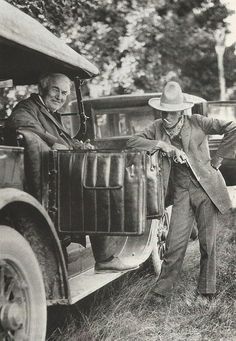 an old black and white photo of two men standing in the back of a car