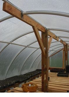 an indoor greenhouse with plants growing in the ground and wooden boards on the floor,