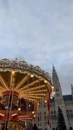 a merry go round in front of a large building with lights on it's sides