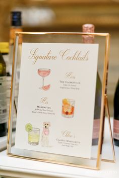 there is a sign that says signature cocktails on the table next to wine bottles