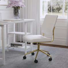 a white desk chair sitting in front of a window next to a vase with purple flowers