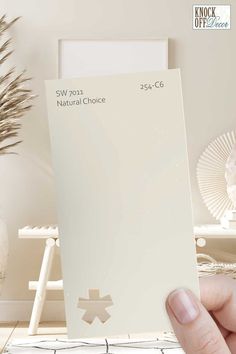 a person holding up a white card with the words natural choice on it in front of a wall