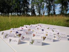 there are cards with flowers on them sitting on a table in front of some tall grass