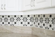 a kitchen counter with black and white tiles on the backsplash, which is decorated with stars