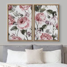 two floral paintings hanging on the wall above a bed