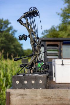 a bow that is sitting on top of a wooden box in front of some trees