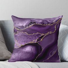 a purple and gold pillow with an abstract design on the front, along with a white background