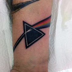 a man's arm with a black triangle and rainbow in the middle on it