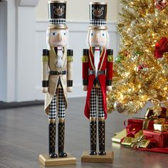 two wooden nutcrackers standing next to a christmas tree