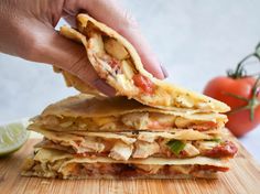 a person is holding a tortilla with meat and cheese on it, next to a slice of lime