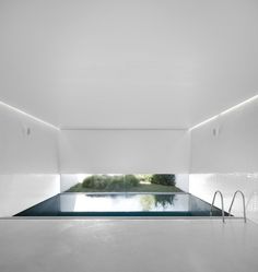 an empty room with a pool in the center and white walls on both sides,