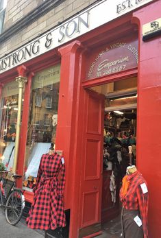 a red store front with mannequins in the window and other clothing on display