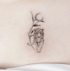 a small tiger tattoo on the back of a woman's stomach, with leaves