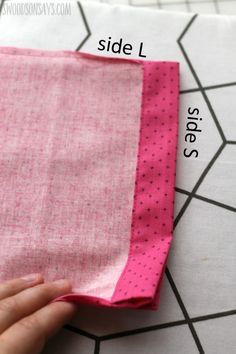 someone is cutting fabric with scissors on top of a piece of cloth that has pink and white polka dots