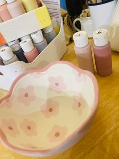 a pink bowl sitting on top of a wooden table next to some bottles and containers