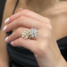 a woman's hand holding an engagement ring with three flowers on the middle and one flower in the middle