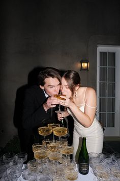 a man and woman standing next to each other with champagne glasses in front of them